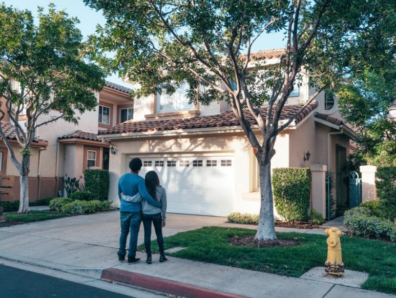  Image of a married couple standing in front of the house they recently bought.
